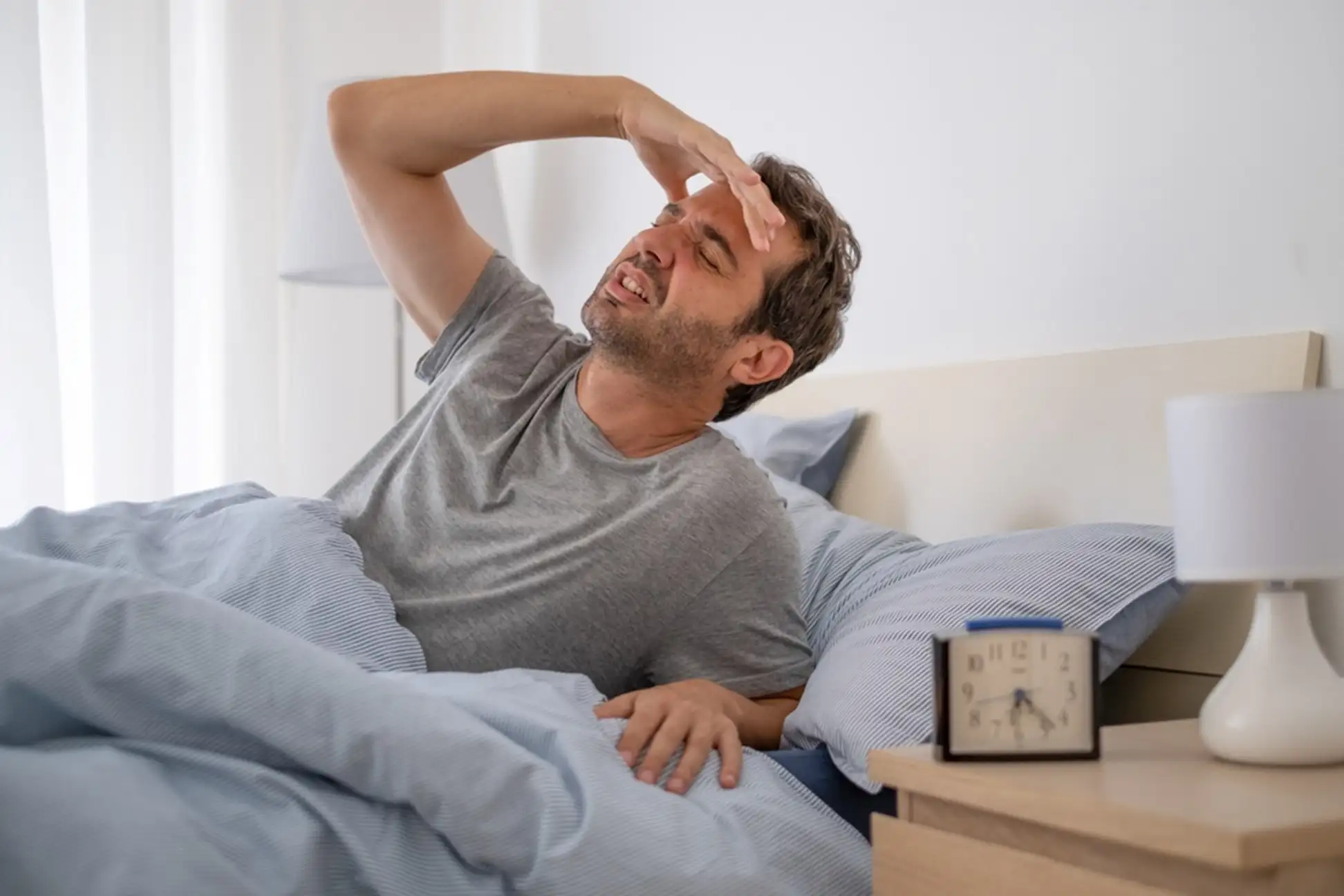 Man laying in bed having a headache