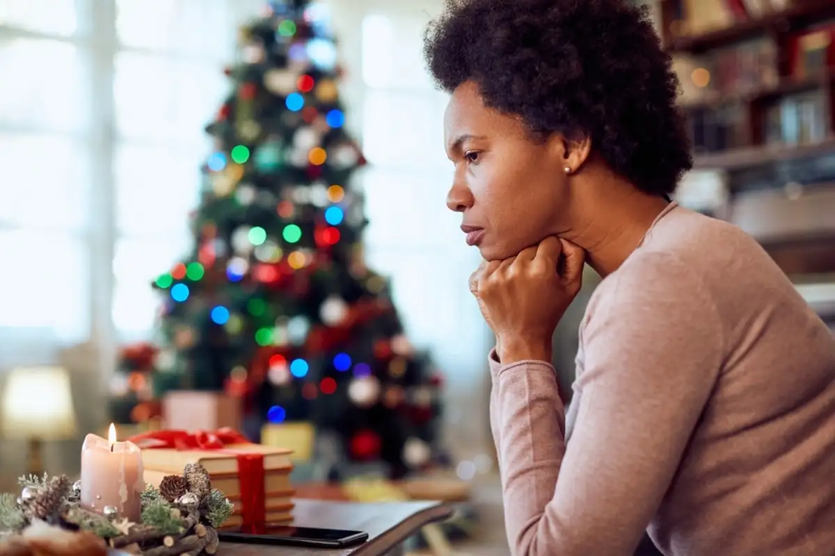 Woman sitting at a table with a christmas tree in the background