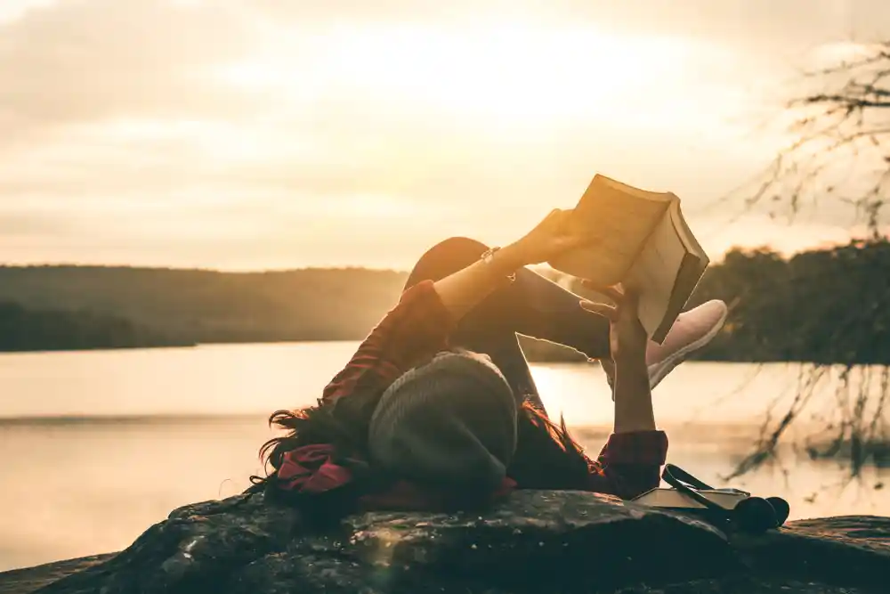 Girl reading a book in a sunset