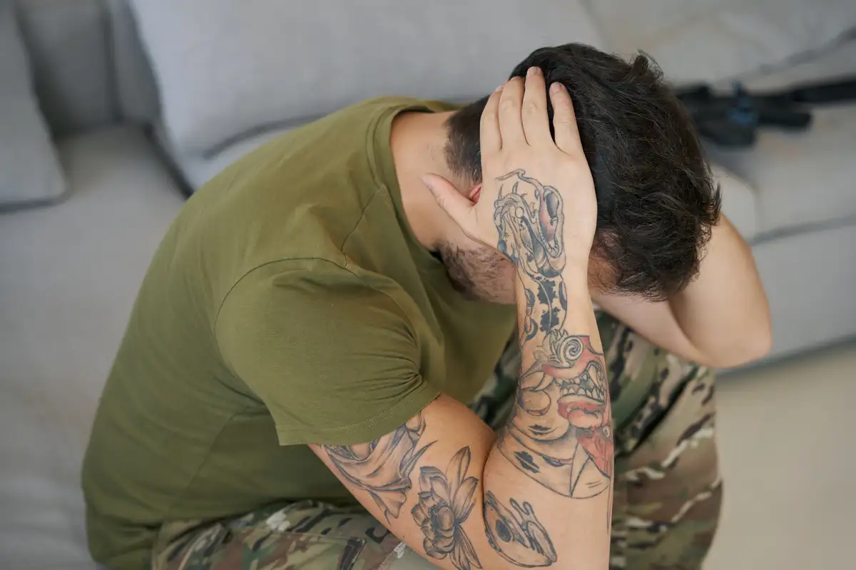 Man sitting on the floor covering his face with his hands